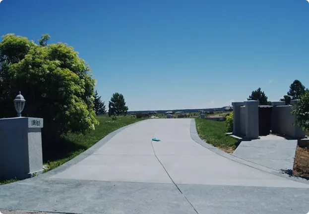 Concrete driveway with caution tape, showcasing a newly installed surface in front of a residential home.