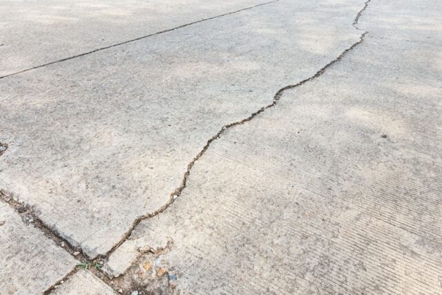 Concrete driveway with caution tape, showcasing a newly installed surface in front of a residential home.