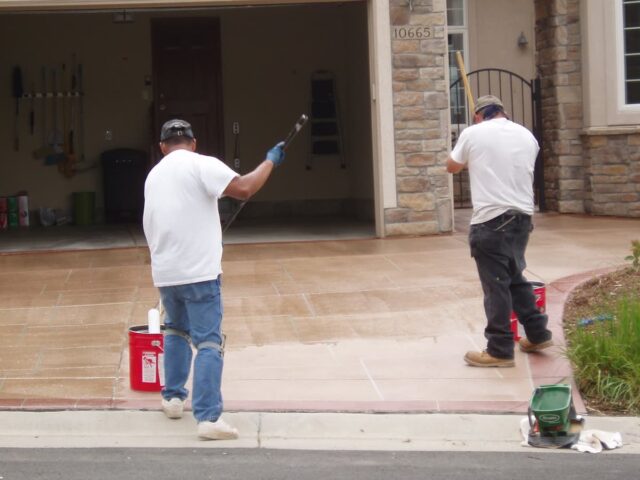 Concrete driveway with caution tape, showcasing a newly installed surface in front of a residential home.